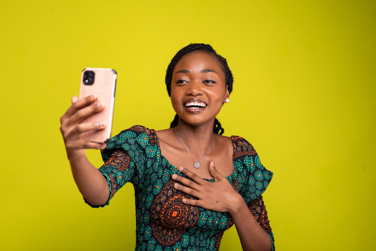 Woman in patterned dress holds smartphone during video call.